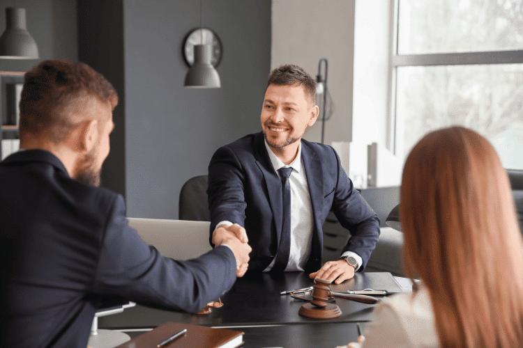 Male lawyer with client shaking hands in office