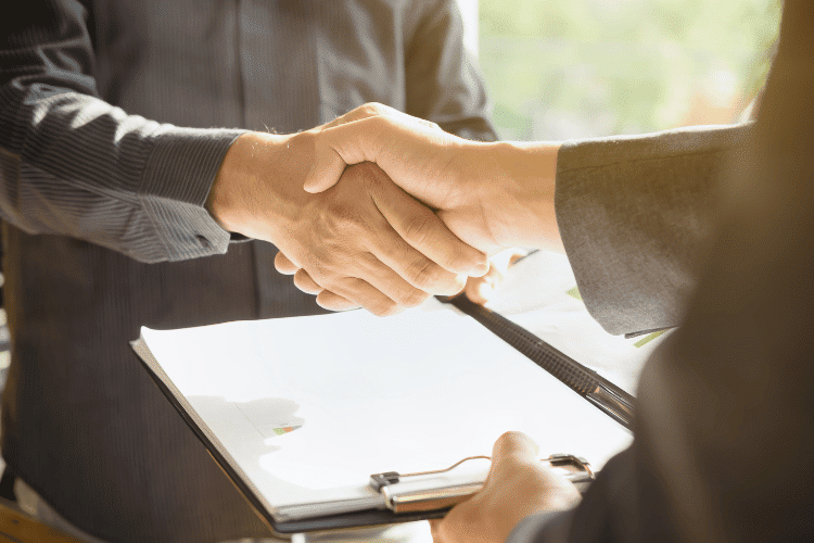 Seller handshaking with a client over a contract agreement, closeup